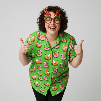 Person with curly hair wearing novelty red antler glasses and a bright green "Sleigh My Name, Sleigh My Name" shirt, smiling and giving two thumbs up against a plain background.