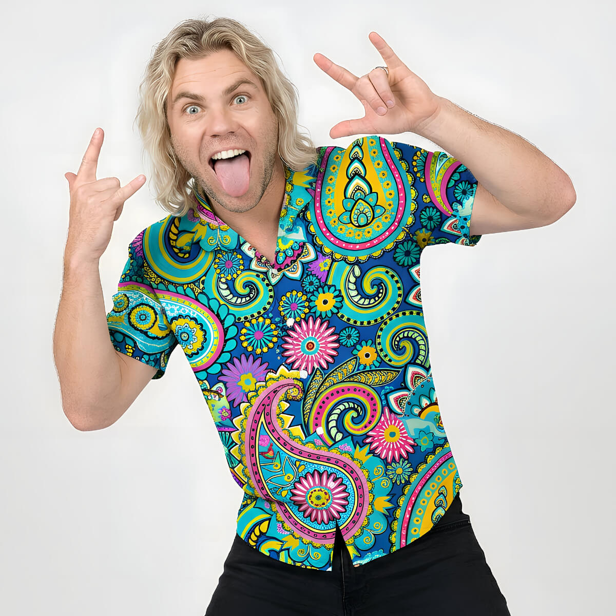 A man with long blonde hair smiles widely, sticking out his tongue and flashing rock-on signs while wearing the Psychedelic Explorer Shirt, which features vibrant paisley and floral patterns on a crisp white background.