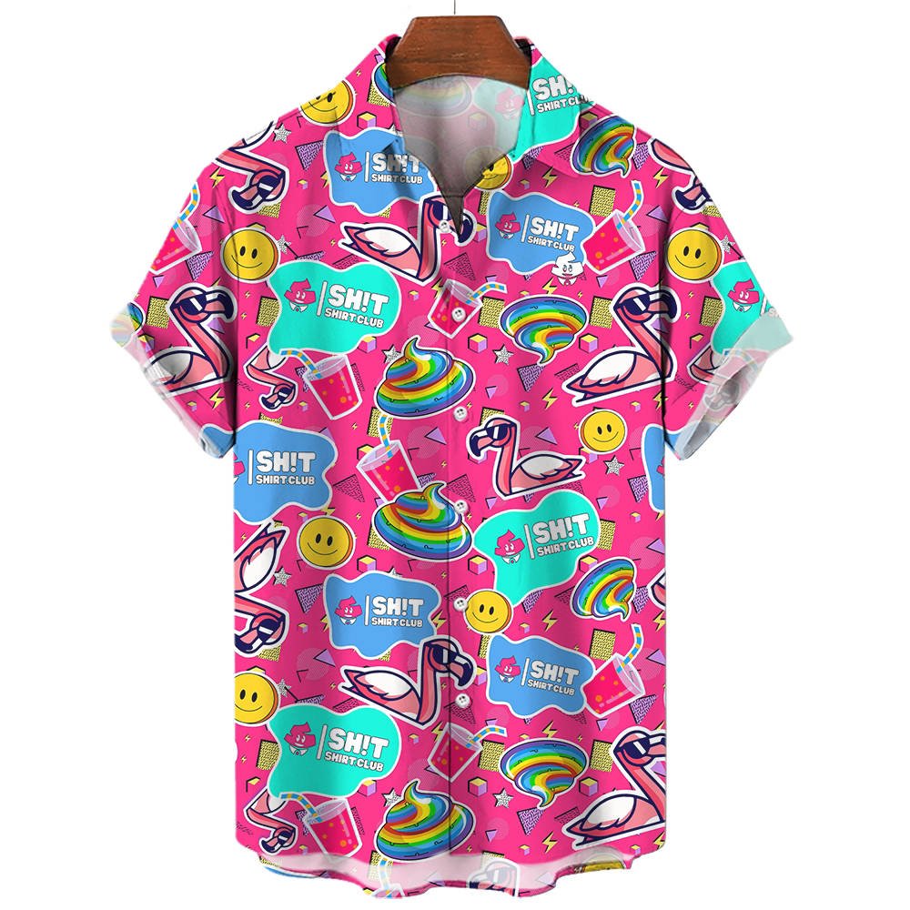 The Badass Shirt is a pink short-sleeve top with colorful cartoon prints—smiling emojis, flamingos, rainbows, rainbow poop, and blue “SH!T SHIRT CLUB” labels. It’s displayed on a wooden hanger against a pink background.